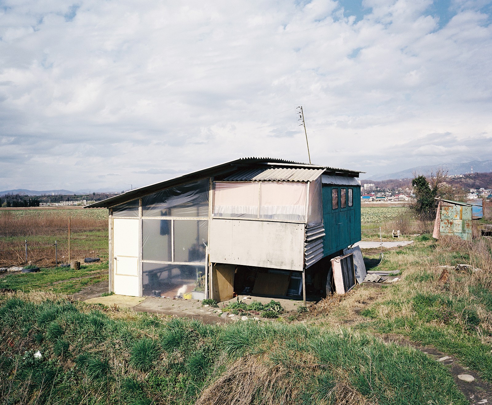 In 2009, state farm 'Russia' was fenced off with a big blue, Olympic fence. Refugees from Abkhazia were allowed to temporarily farm the land. They lived in this caravan.
